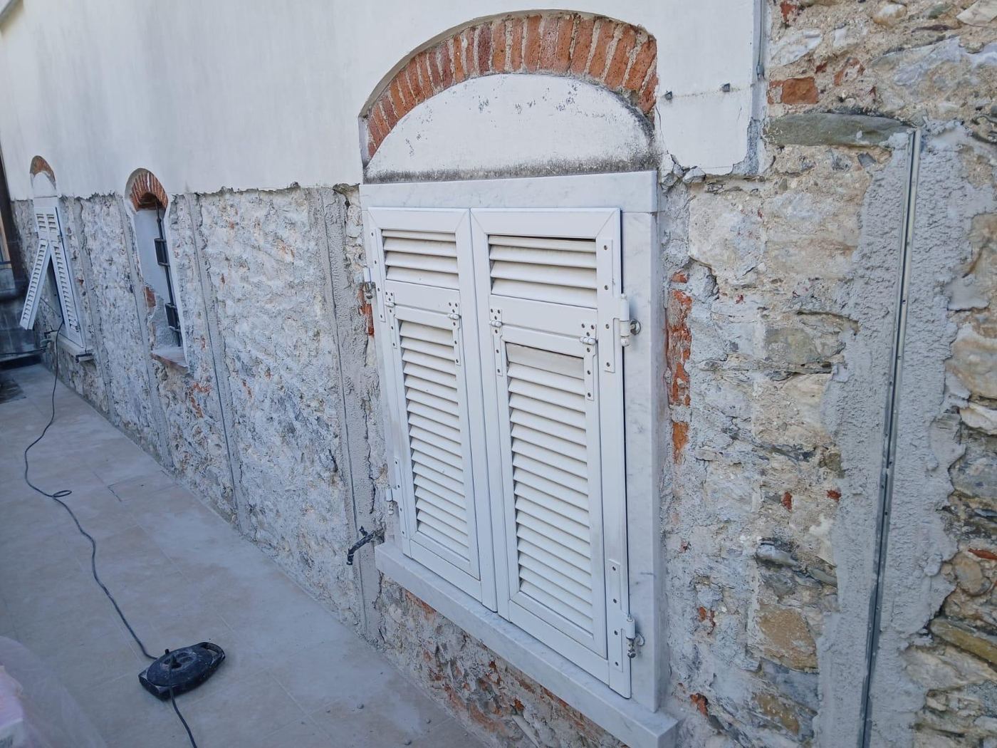 Finestra con cornice in marmo su muro in pietra a vista, prima dell'intonacatura